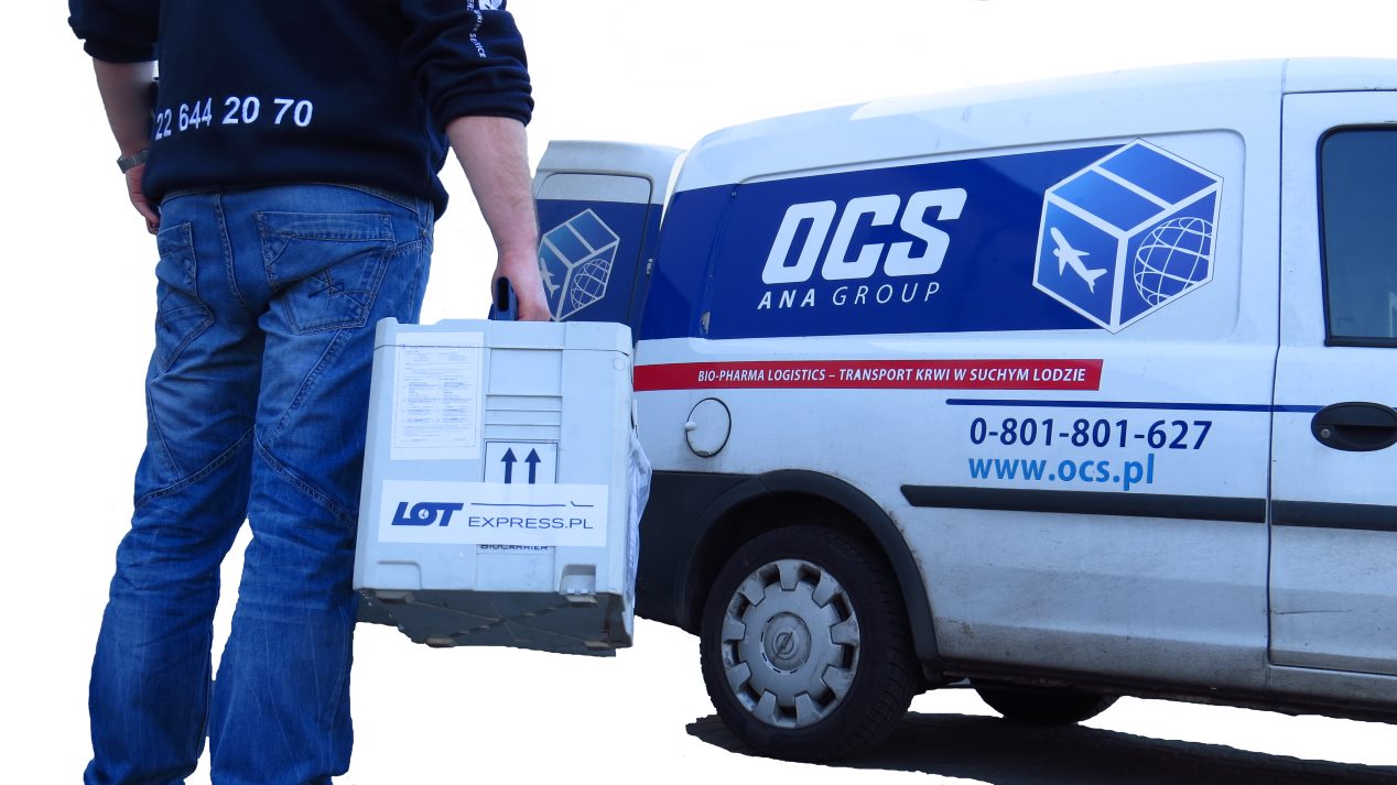 Kurier OCS niesie przesyłkę w specjalnym kufrze do samochodu firmy OCS przeznaczonego do transportu w suchym lodzie
